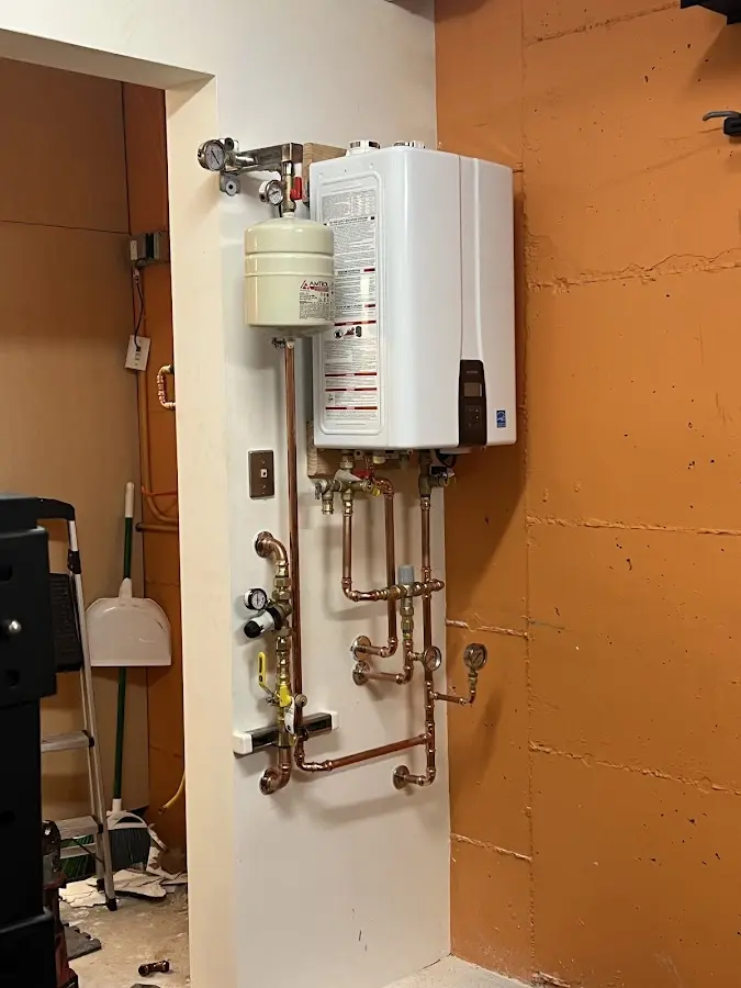 Plumbing technician inspecting water heater connections in Sandown